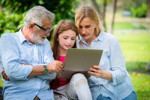 Famille heureuse utilisant un ordinateur portable dans le parc public
. - Photo, image