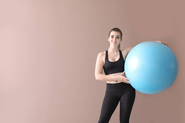 Young sporty woman with fitball on color background - Zdjęcie, obraz