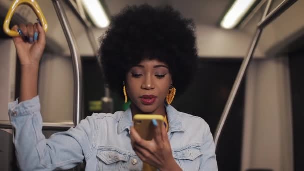 Young african american woman using smart phone voice recognition, dictates thoughts, voice dialing message riding in the public transport. - Felvétel, videó