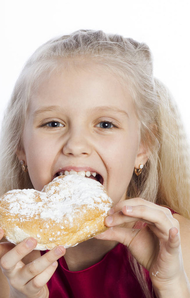 Girl biting a heart-shaped biscuit - 写真・画像
