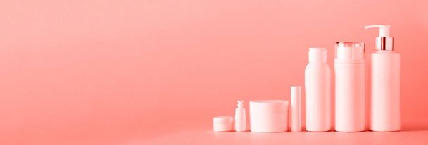White cosmetic tubes on trendy coral color background with copy space. Skin care, body treatment, beauty concept. Banner - Photo, Image