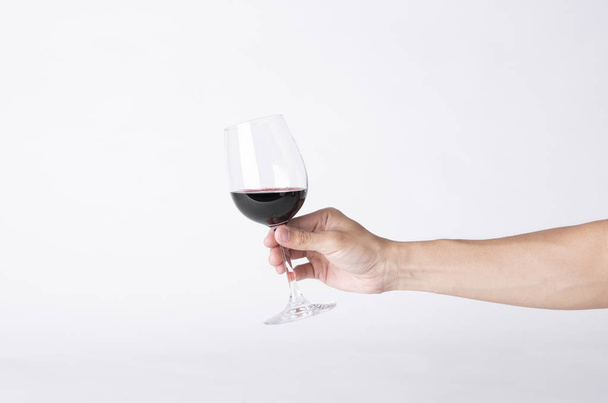 Man hand houden van een wijn glas op een grijze achtergrond.  - Foto, afbeelding