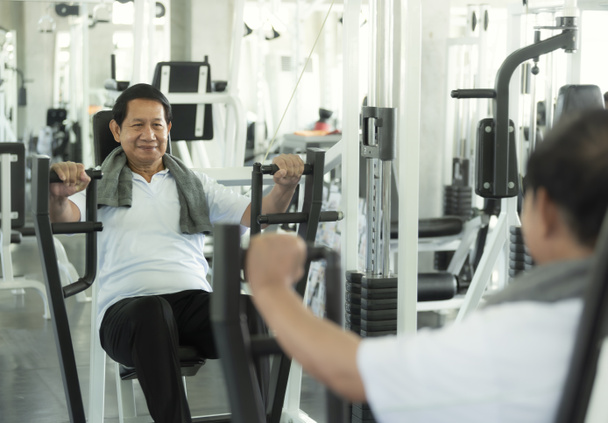 Fitness salonunda Asyalı yaşlı adam egzersiz halter kaldırma.  - Fotoğraf, Görsel