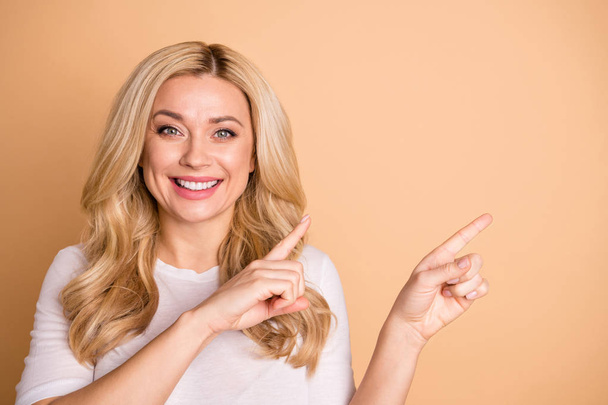 Close-up portrait of her she nice-looking lovely winsome attractive cheerful cheery wavy-haired lady pointing two forefingers aside promotion solution isolated over beige pastel background - Foto, Imagem