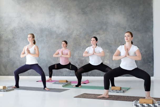 Grupo de estudiantes de yoga concentrados haciendo pose de rudrasana o diosa
 - Foto, imagen
