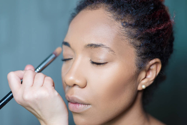 professional make-up makeup artist apply makeup to a dark-skinned woman - Fotografie, Obrázek
