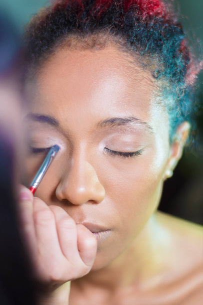 professional make-up makeup artist apply makeup to a dark-skinned woman - Фото, изображение