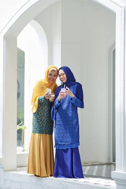 Csinos fiatal muzulmán nők látszó-on smartphone  - Fotó, kép