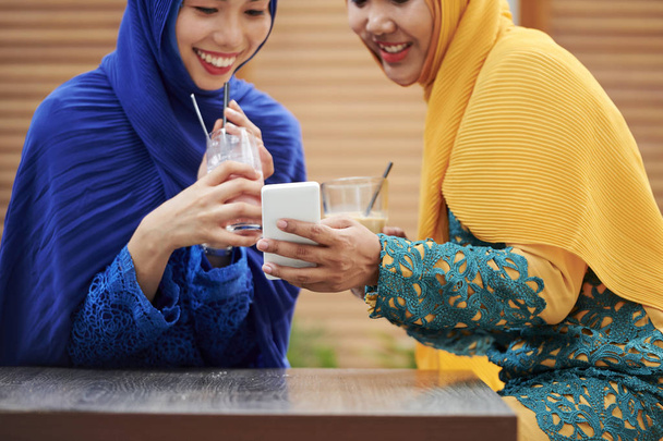 Όμορφη νεαρή γυναίκα σε παραδοσιακά μουσουλμανικά φορέματα πίνοντας κοκτέιλ και παίρνοντας selfie - Φωτογραφία, εικόνα
