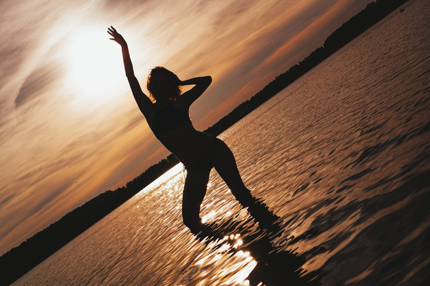 Щаслива безтурботна жінка, яка насолоджується чудовим заходом сонця на березі моря - Фото, зображення