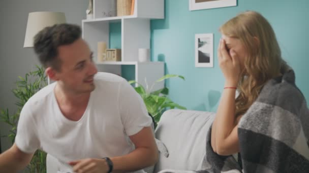 Young man gives a gift to a happy girlfriend in the morning in the living room - Filmagem, Vídeo