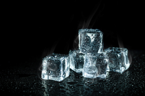 ice cubes and cooling smoke on dark table background. Ice blocks with cold drinks. - Photo, Image