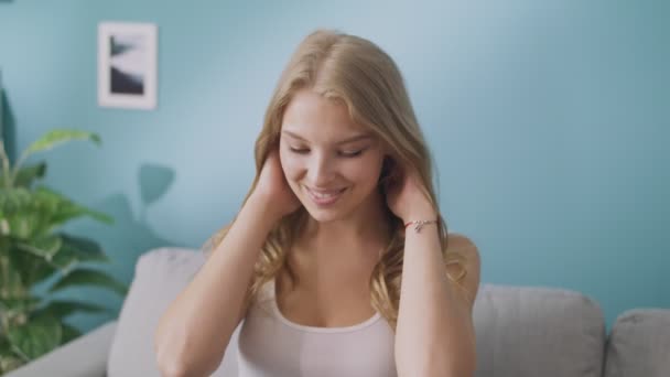 Portrait of happy young lady looking at camera and smiling in cozy living room - Materiaali, video