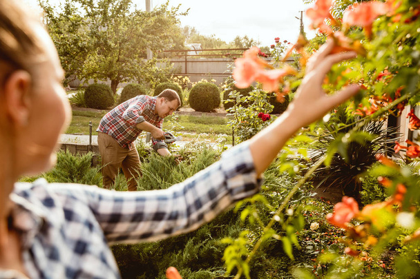 Jong en gelukkig boeren paar in hun tuin in zonnige dag - Foto, afbeelding
