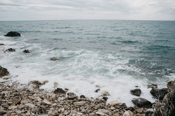 Rusteloze zee in de buurt van de stenen kust. - Foto, afbeelding