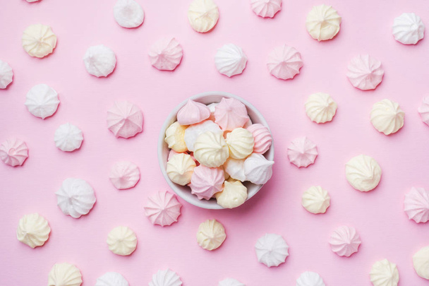 Colored small meringues on a pink background. Flat lay concept. Copy space. - Fotó, kép