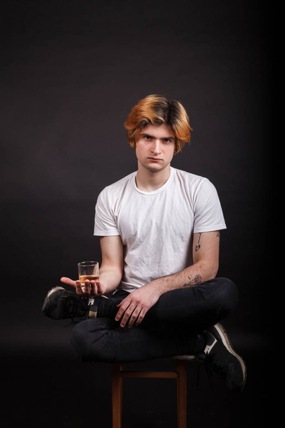 Jovem adulto caucasiano com cabelo loiro segurando uísque na mão
 - Foto, Imagem