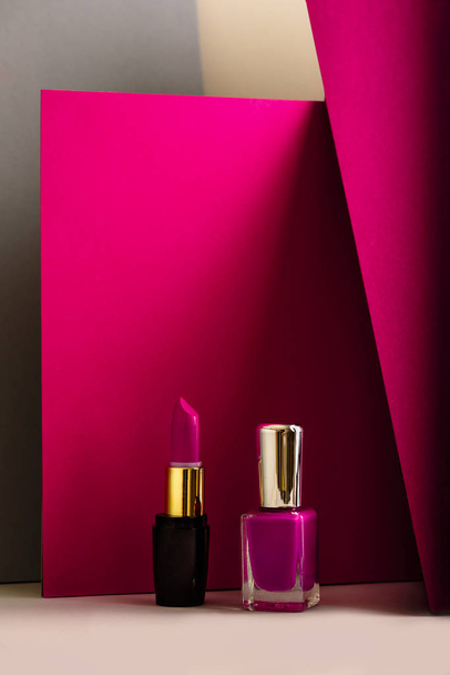 set of lipstick and nail polish, on modern colored background - 写真・画像