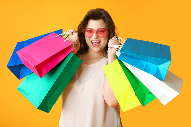 Happy plus size woman with shopping bags on color background - Fotografie, Obrázek