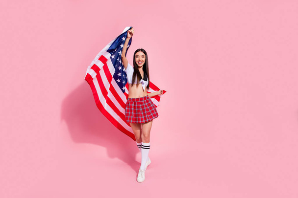 Full photo of pretty lady hold united states flag student party excited wear white top short plaid skirt isolated pink background - Photo, Image