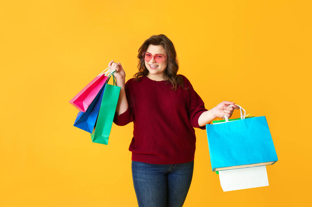 Happy plus size woman with shopping bags on color background - Photo, Image