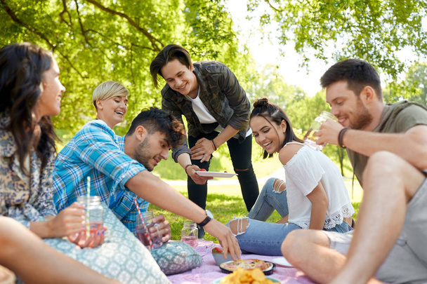friends with drinks and food at picnic in park - Photo, Image