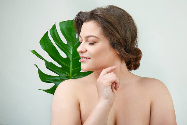 Portret pięknej kobiety plus size z tropikalnym liści na jasnym tle - Zdjęcie, obraz