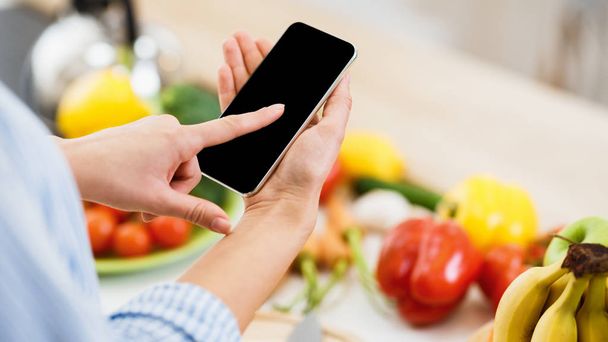 Search recipe. Woman using smartphone, cooking food - Photo, Image