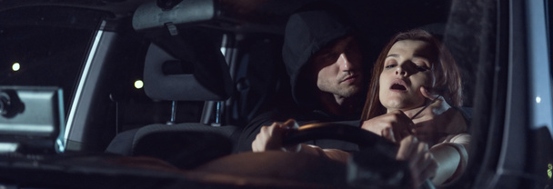 панорамний знімок злодія, що задушує перелякану жінку в автомобілі вночі з ножем
 - Фото, зображення