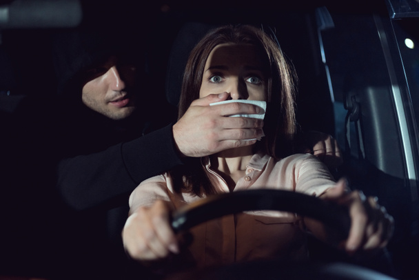 thief attacking beautiful frightened woman in car at night - Φωτογραφία, εικόνα