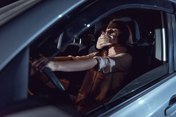 Dieb verdeckt nachts Mund einer verängstigten Frau im Auto - Foto, Bild