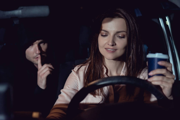 車の中で美しい笑顔の女性の近くでサイレントジェスチャーをしている泥棒 - 写真・画像
