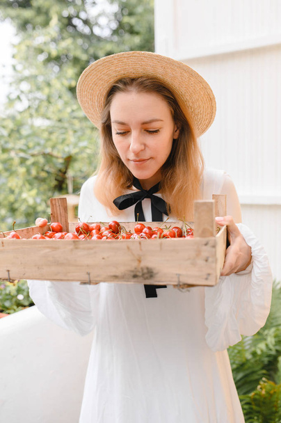 happy woman with cherries wearing hat and white dress. Healthy eating, dieting, vegetarian food and people concept - Photo, Image