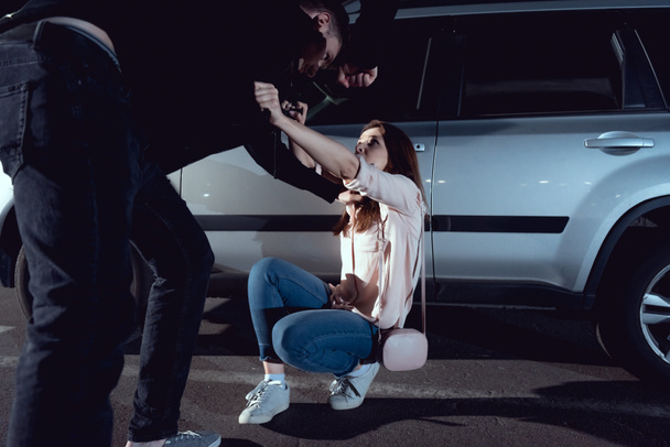 thief attacking scared woman near car at night - Zdjęcie, obraz