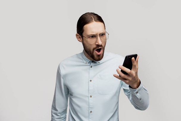 Crazy shocking businessman having a bad call, problem with connect, slowly internet connection. Technology concept, free wifi. American hipster over white studio background - Zdjęcie, obraz
