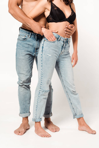 cropped view of shirtless man standing with girl in blue jeans on white  - Valokuva, kuva