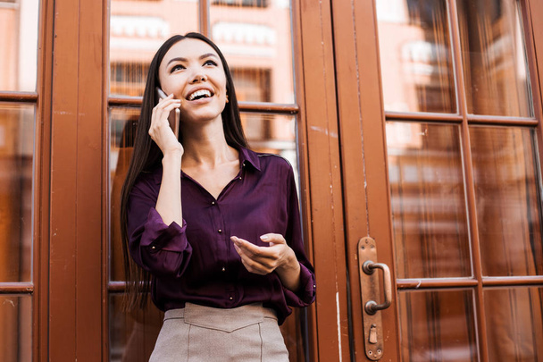 Приваблива брюнетка азіатська бізнес-леді розмовляє по мобільному телефону з клієнтом. Впевнений і успішний працівник, менеджер викликів, оператор, зв'язок онлайн
 - Фото, зображення