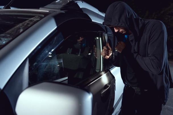 ladrón coche intruso con linterna y palanca en la noche
 - Foto, imagen