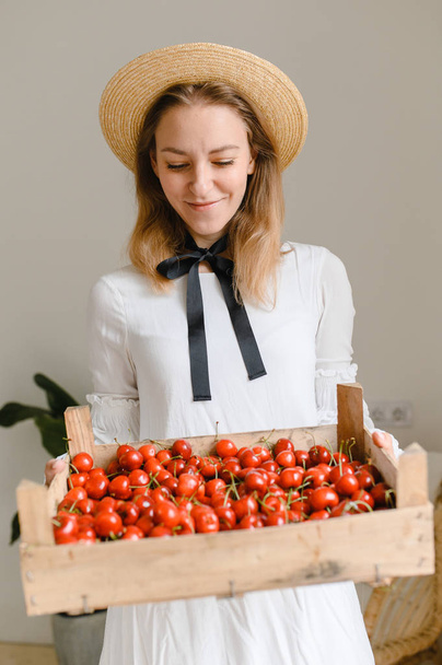 happy woman with cherries wearing hat and white dress. Healthy eating, dieting, vegetarian food and people concept - Fotografie, Obrázek