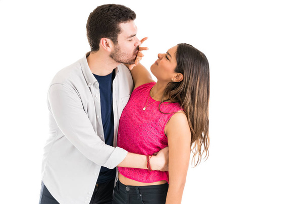 homem afetuoso beijando enquanto sendo parado por mulher descontente com a mão contra fundo branco
 - Foto, Imagem