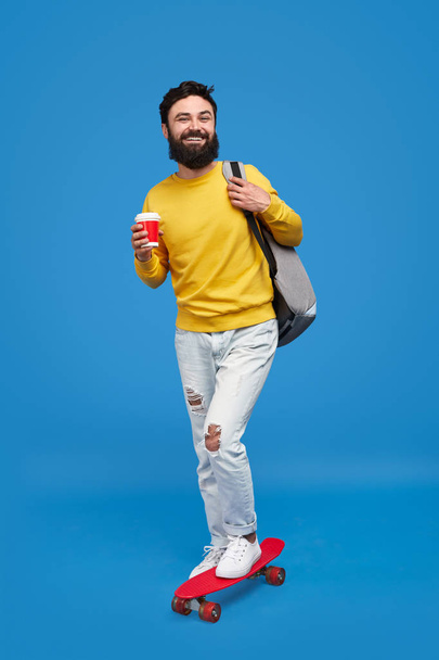 Hipster with beverage riding longboard - Foto, Bild
