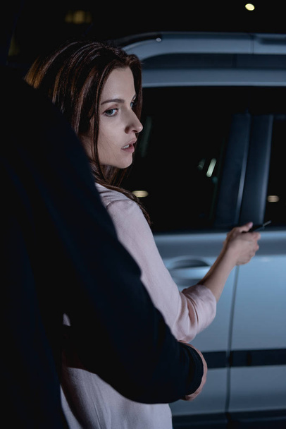 thief attacking woman from behind near car at night - Zdjęcie, obraz