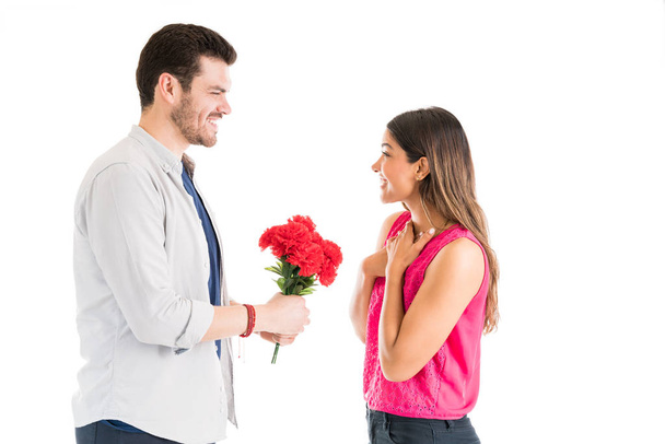 Cheerful young woman receiving flower bouquet from smiling boyfriend against plain background - Photo, Image