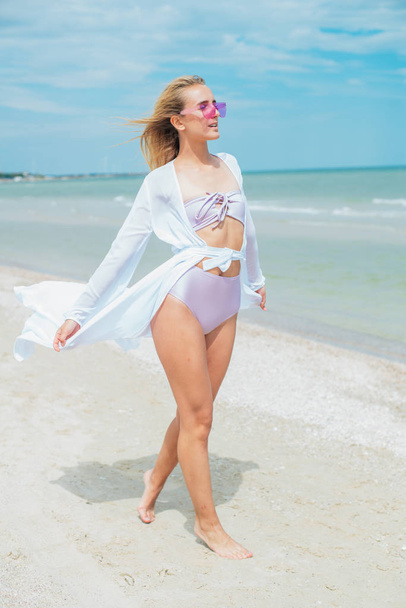 Young woman in  pink swimsuit and sunglasses relax on beach in the sea in sunny hot day - Foto, Imagem