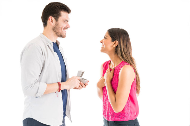 Happy Hispanic boyfriend proposing girlfriend with engagement ring while looking at her in studio - 写真・画像