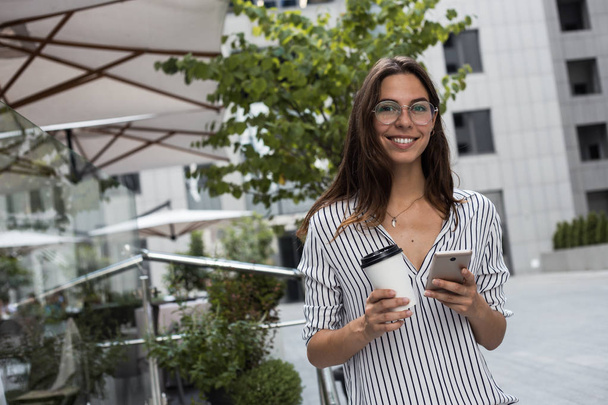 junge schöne Geschäftsfrau, die draußen auf der Straße steht, mit App für Taxiservice und Offline-Karten, kostenlosem Wifi-Zugang und Offline-Diensten für das Reisekonzept - Foto, Bild