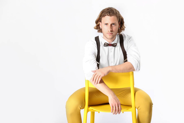 Stylish young man sitting on chair against white background - Fotoğraf, Görsel