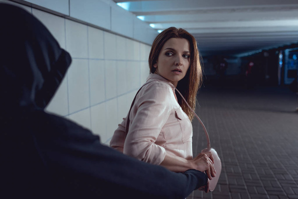 thief stealing bag from beautiful woman in underpass - Foto, imagen