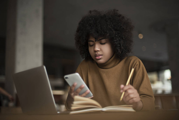 Молодий робітник, стажист, афро-американської жінки, працює на ноутбуці, шукає інформацію за допомогою інтернет-ресурсів, соціальних мереж. Робота за комп'ютером в офісі - Фото, зображення
