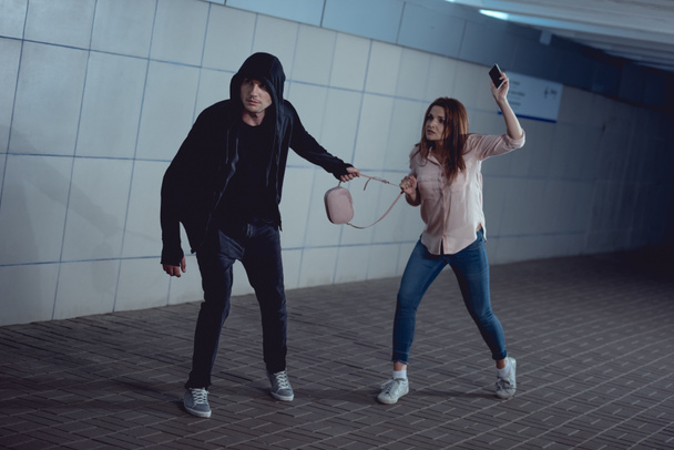 thief stealing bag from woman in underpass - Fotografie, Obrázek